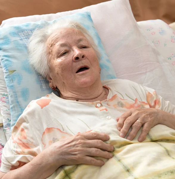 Старшая женщина лежит в постели — стоковое фото