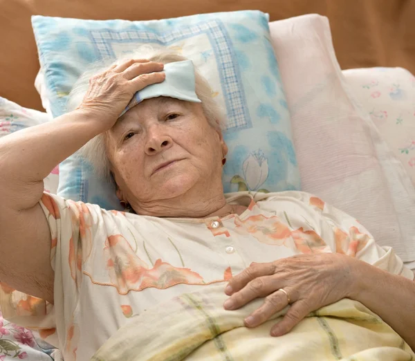 Äldre kvinna liggande på sängen — Stockfoto