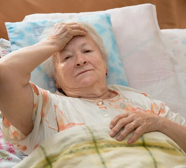 Äldre kvinna liggande på sängen — Stockfoto