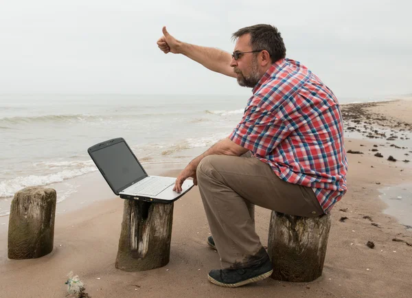 Эмоциональный бизнесмен с ноутбуком на пляже — стоковое фото
