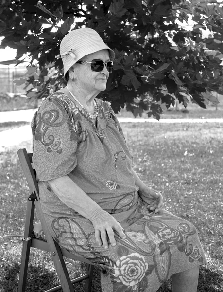 Mulher velha sentada em uma cadeira — Fotografia de Stock