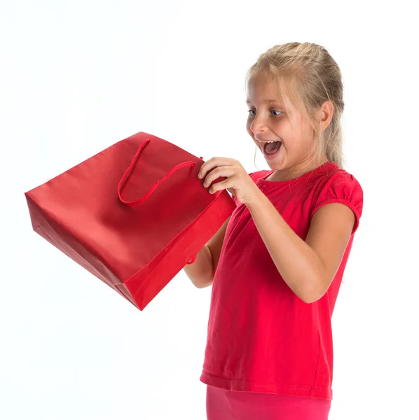 Aufregendes kleines Mädchen schaut in Einkaufstasche — Stockfoto