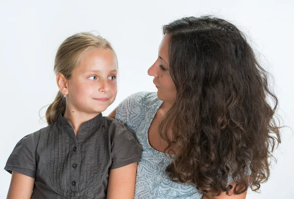 Smiling mother and daughter looking into each other on a white b — Stock Photo, Image