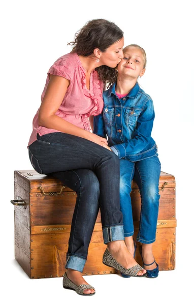 Mother and daughter sitting on a wooden chest — Stock Photo, Image