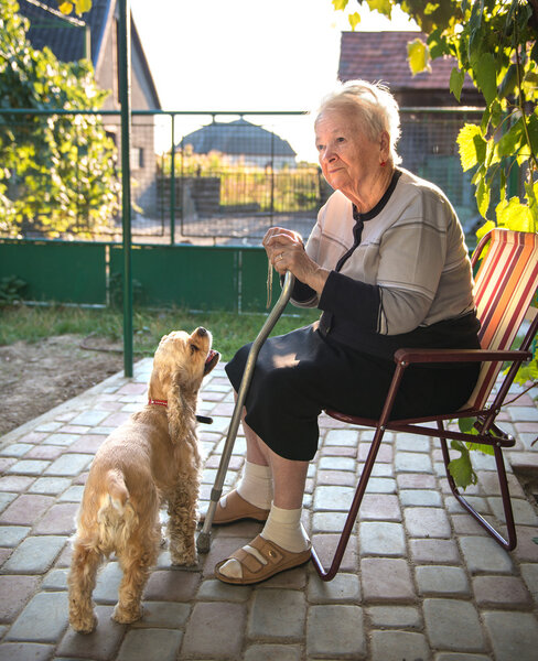 Старуха сидит на стуле с тростью
