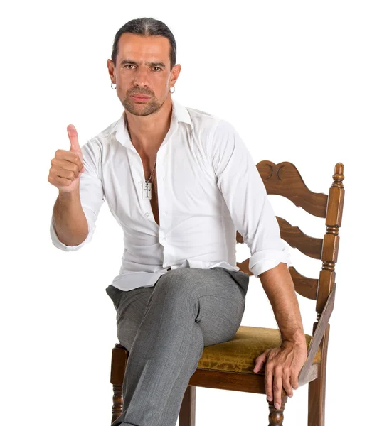 Bonito homem sentado em uma cadeira e mostrando sinal ok — Fotografia de Stock