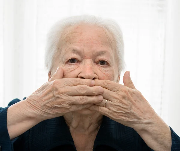 Starszy kobieta trzymając się za ręce na usta — Zdjęcie stockowe