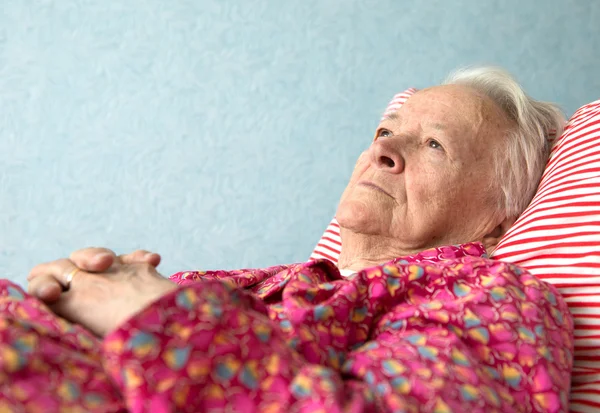 Yaşlı hasta bir kadın yatakta yatan — Stok fotoğraf