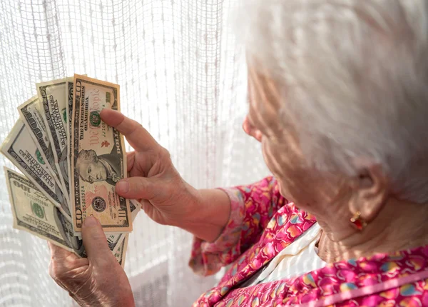 Old woman holding money in hands — Stock Photo, Image