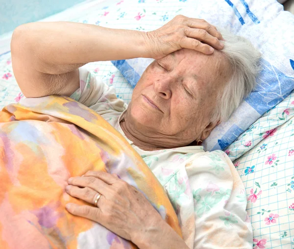 Gammal sjuk kvinna liggande på sängen — Stockfoto