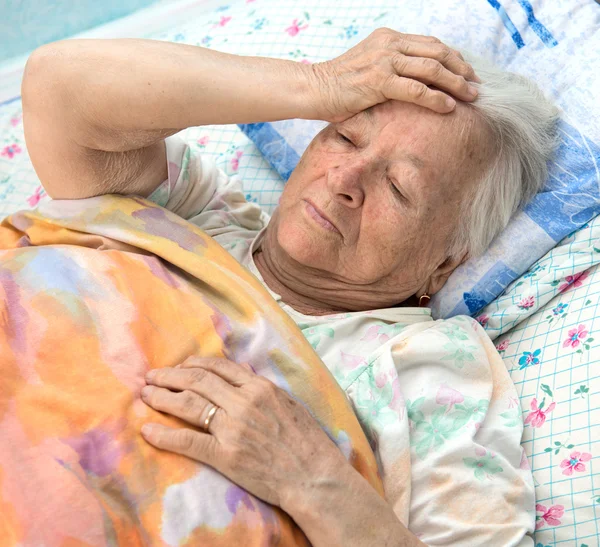 Alte kranke Frau liegt im Bett — Stockfoto