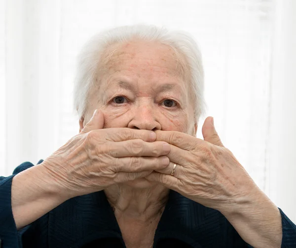 Senior mulher de mãos dadas sobre a boca — Fotografia de Stock