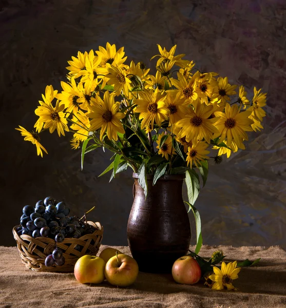 Bunch of yellow flowers (rudbeckia) in brown vase and fruits