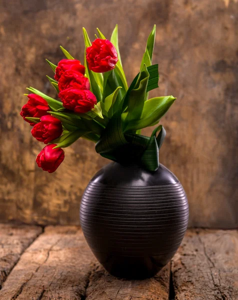 Beautiful red tulips in black vase — Stock Photo, Image