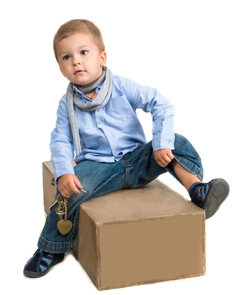 Pequeno menino sentado em uma caixa — Fotografia de Stock