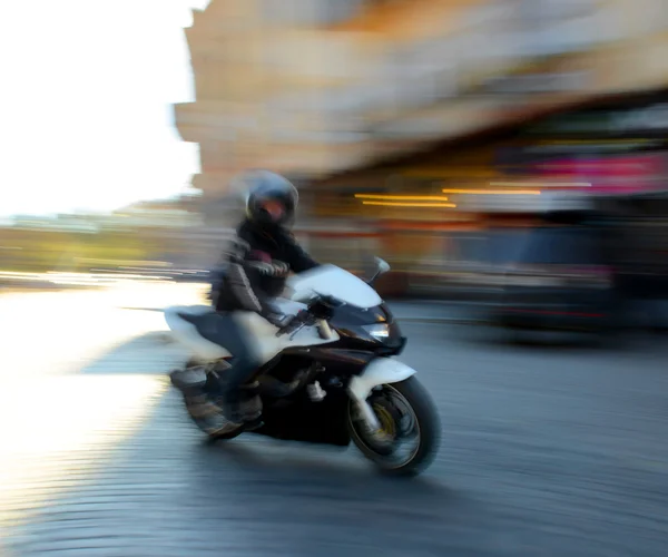 Motorcyclist in motion going down the street Stock Image