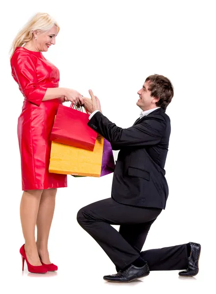 Handsome man on knees presenting woman gifts — Stock Photo, Image