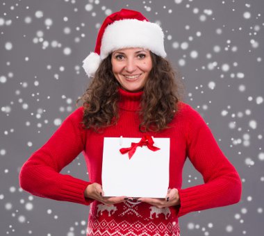Noel Baba şapkası ile alışveriş çantası içinde gülümseyen kadın