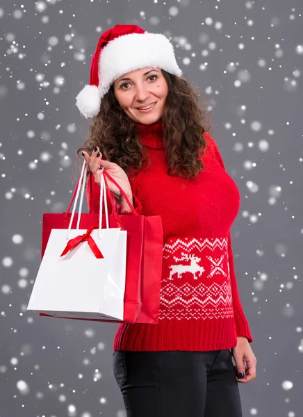 Noel Baba şapkası ile alışveriş çantası içinde gülümseyen kadın — Stok fotoğraf
