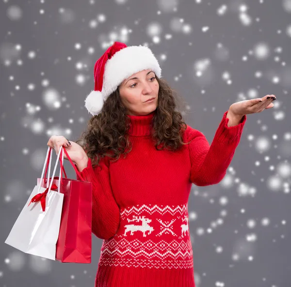 Donna sorridente in cappello di Babbo Natale con borse della spesa — Foto Stock