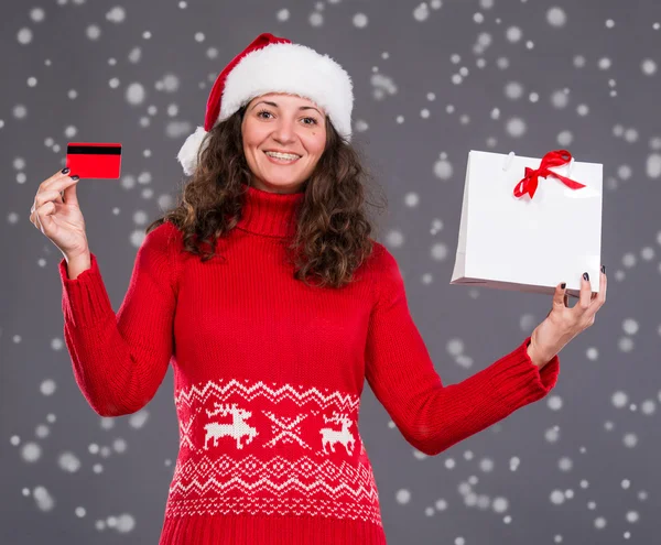 Femme souriante en chapeau de Père Noël avec sac à provisions — Photo