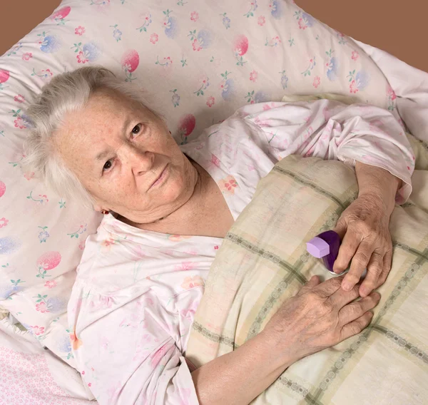 Sjukt gammal kvinna liggande på sängen — Stockfoto