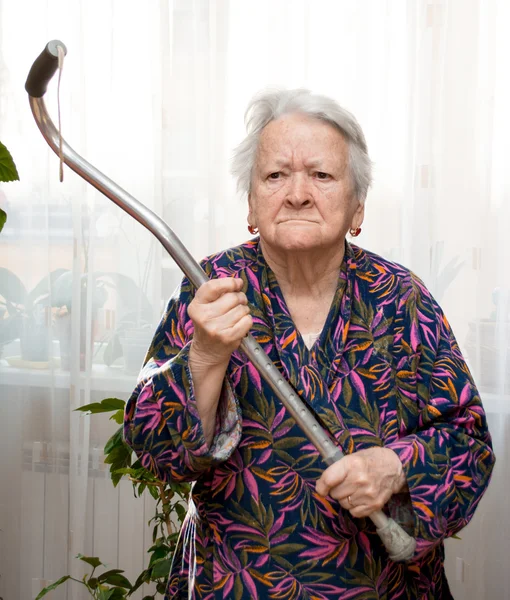 Vecchia donna arrabbiata che minaccia con un bastone — Foto Stock