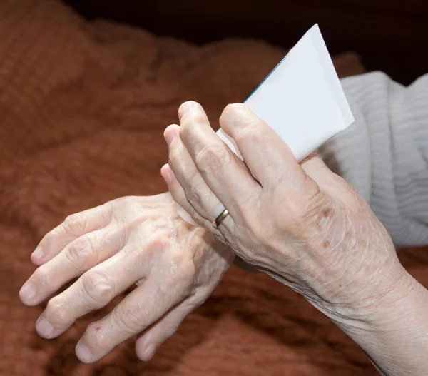 Seniorenhände cremen sich ein — Stockfoto