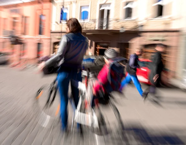 通りを下って行く自転車に子供を持つ女性 — ストック写真