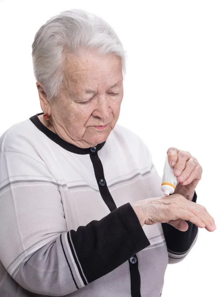 ผู้หญิงแก่ใช้ครีมทามือ — ภาพถ่ายสต็อก