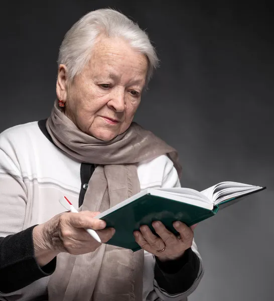 Senior vrouw schrijven van notities in een notitieblok — Stockfoto