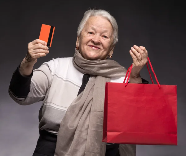 Happy old woman with shopping bags and credit card — Stock Photo, Image