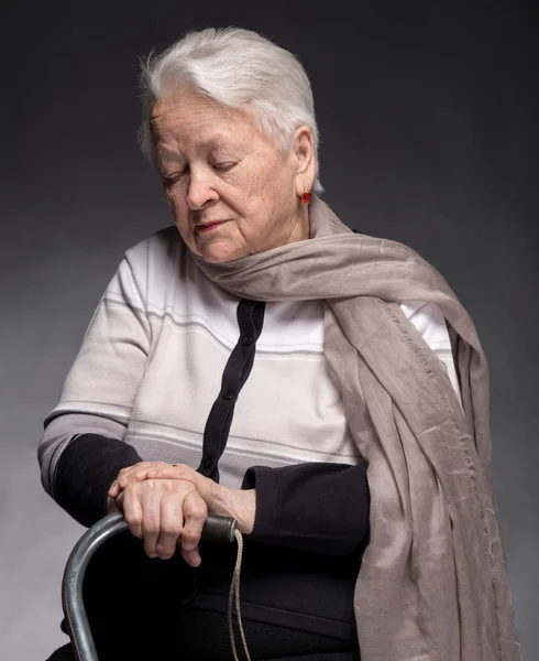 Alte Frau sitzt mit einem Stock — Stockfoto