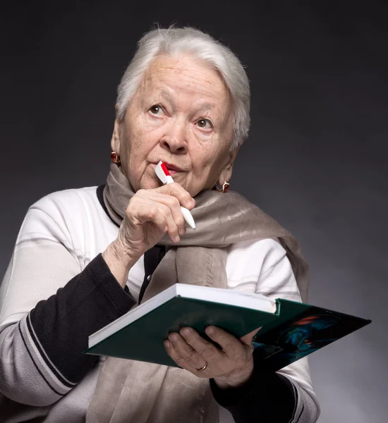 Mulher sênior escrevendo notas em um caderno — Fotografia de Stock