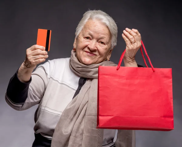 Happy old woman with shopping bags and credit card — Stock Photo, Image