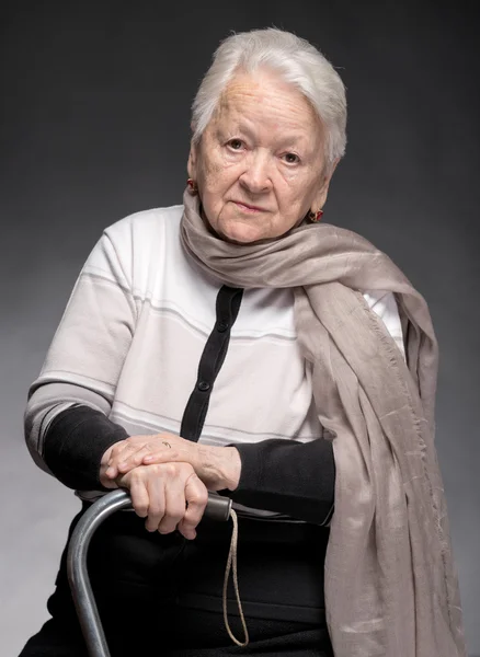 Portrait of old woman sitting with a cane — Stock Photo, Image