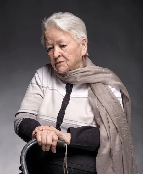 Portret van oude vrouw zitten met een stok — Stockfoto