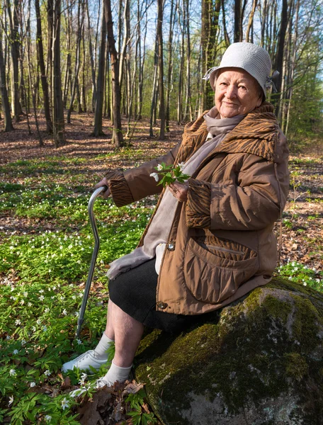 Alte Frau sitzt auf einem Baumstumpf — Stockfoto