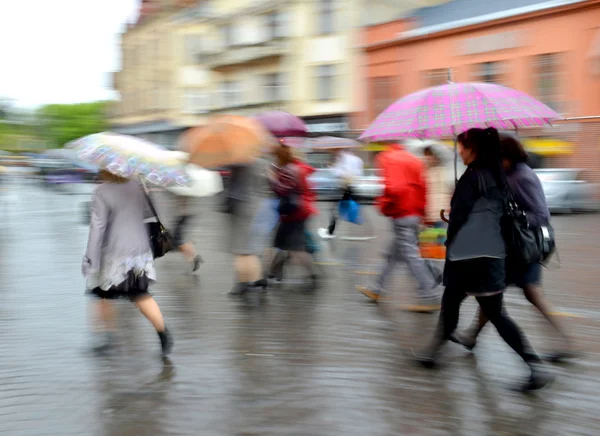 Gruppe von Menschen, die bei regnerischem Wetter die Straße entlang laufen — Stockfoto