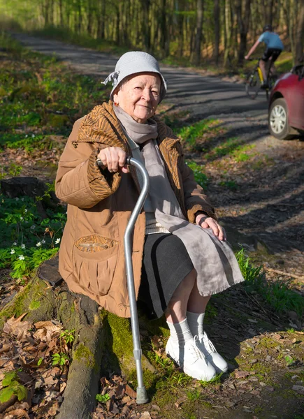 Alte Frau sitzt auf einem Baumstumpf — Stockfoto