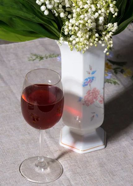 Lys de la vallée dans un vase et un verre de vin — Photo