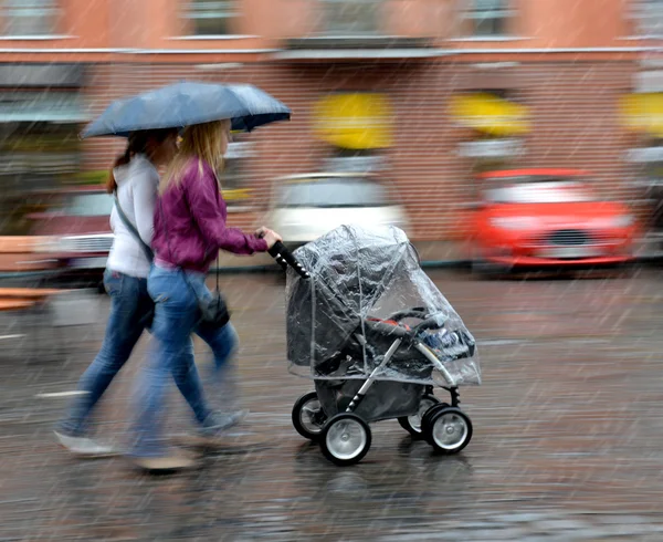 La mamma cammina con il bambino nel passeggino in un giorno di pioggia — Foto Stock