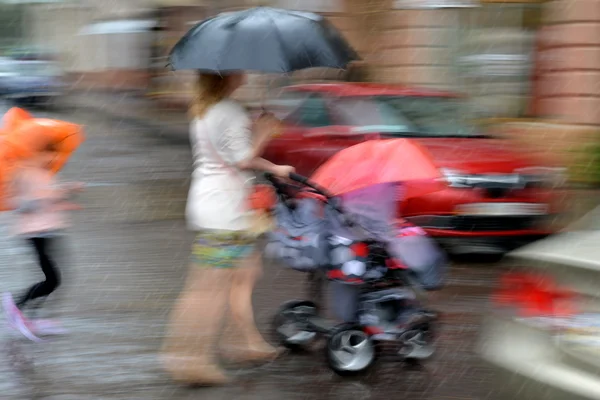Matka chodí s dítětem v kočárku na deštivý den — Stock fotografie