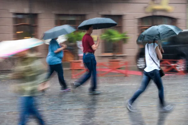 Gruppe von Menschen, die an einem regnerischen Tag in Bewegung die Straße entlang gehen — Stockfoto