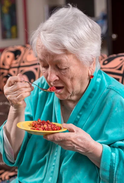 Old woman eating strawberry — Stock Photo, Image