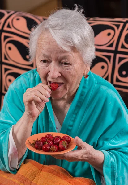 딸기 먹는 늙은 여자 — 스톡 사진