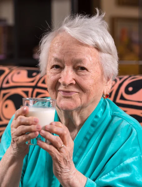 Stara kobieta gospodarstwo mleczne szkło — Zdjęcie stockowe
