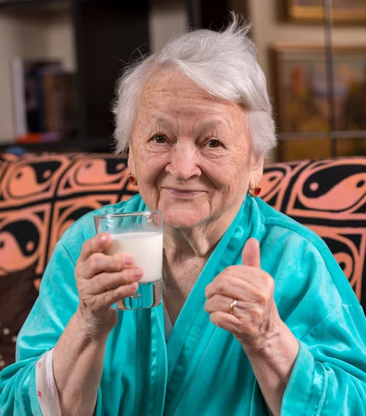 Old woman holding a glass milk — Stock Photo, Image