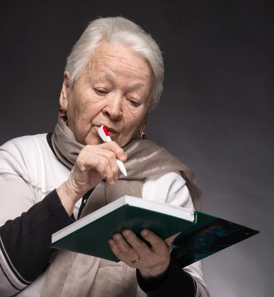 Senior vrouw schrijven van notities in een notitieblok — Stockfoto