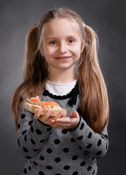 Glückliches kleines Mädchen, das Brot und Butter mit Fisch isst — Stockfoto